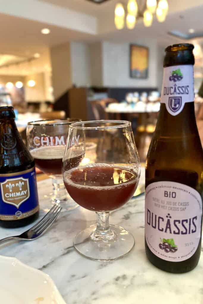 Bottle of blackcurrant beer with some poured out in a glass.