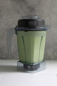 Kale protein smoothie, a pale green mixture in blender after being blended.