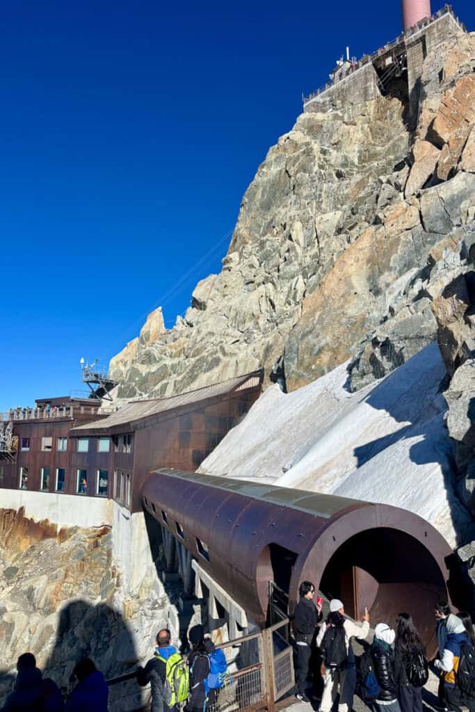 Tourists gather near tunnel opening at viewing platform.