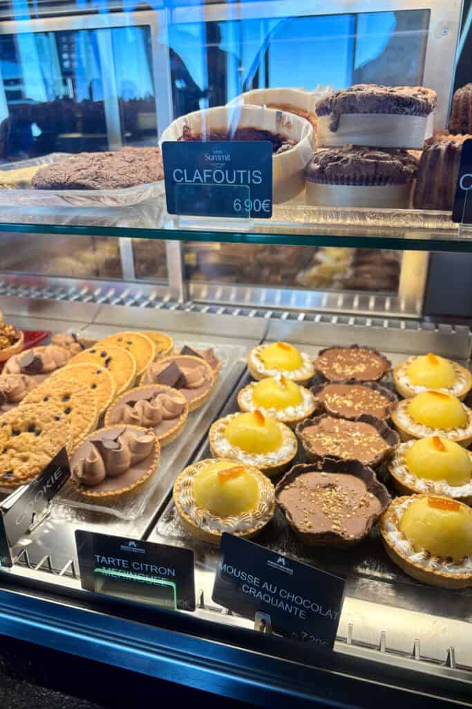 Clafoutis, cookies, tarts, and chocolate mousse in cafeteria display case.