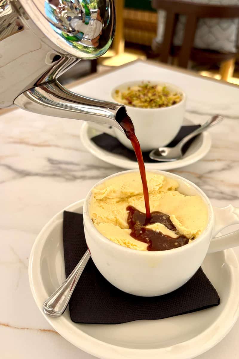 Pouring espresso from kettle over bowl of ice cream to make affogato.