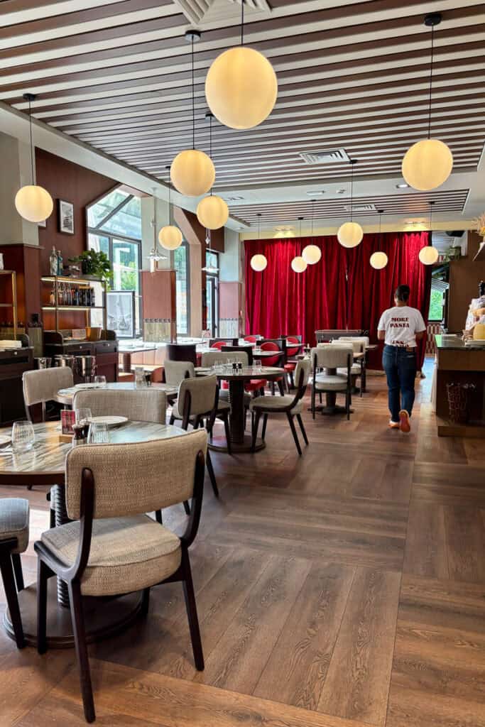 Indoor dining area at Casa Nonna with hanging globe lights and a red curtained wall at one end.