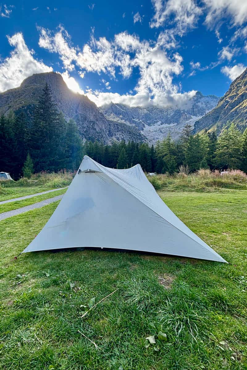Pitched backpacking tent for camping the Tour du Mont Blanc with mountains rising in the background.