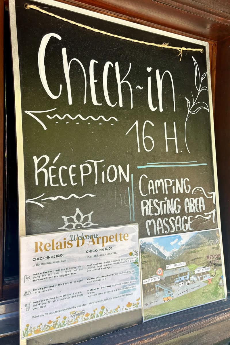 Sign explaining check-in time and visitor facilities while camping the Tour de Mont Blanc at the Relais d'Arpette.
