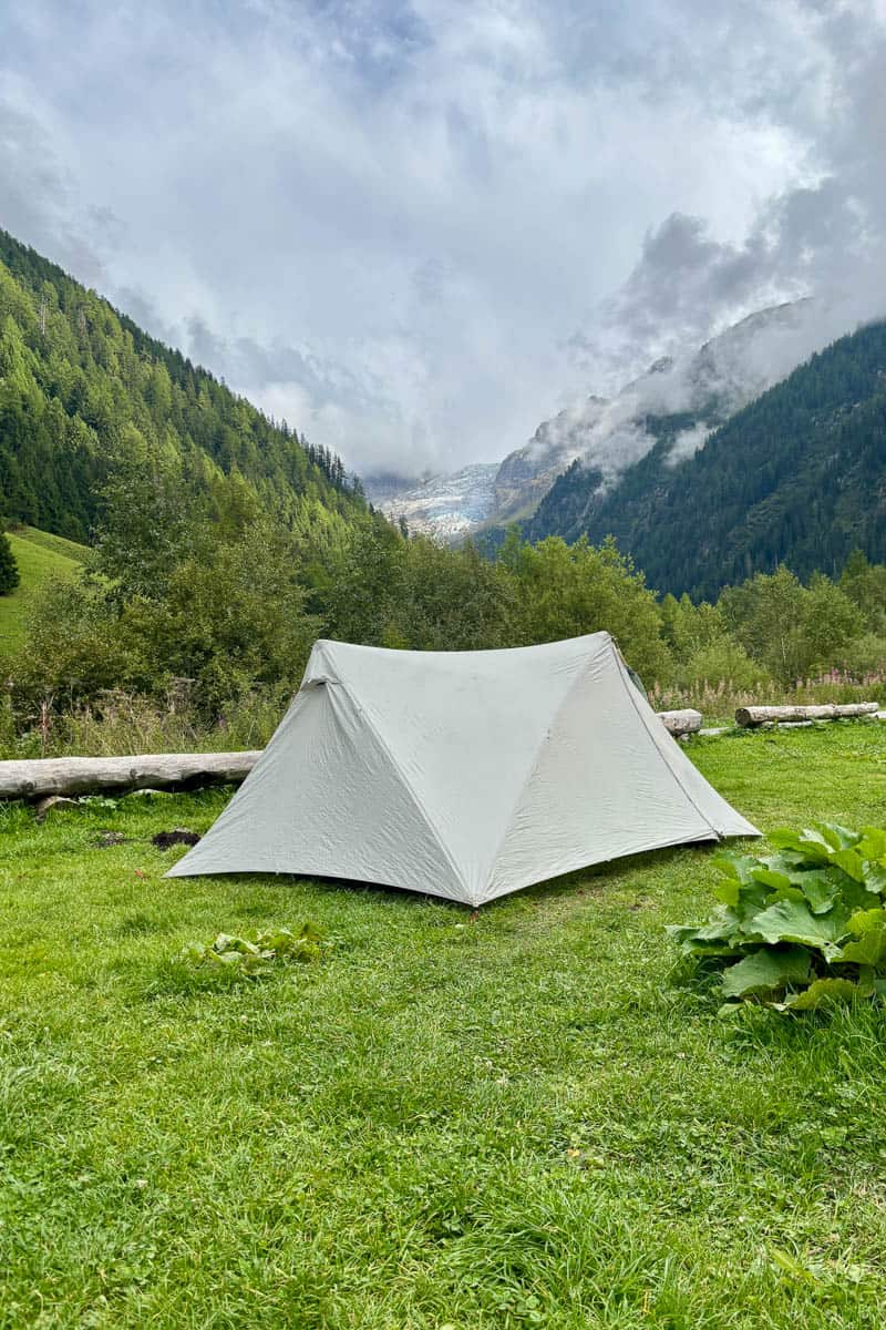 Backpacking tent pitched with view of forested mountainsides while camping the Tour du Mont Blanc.
