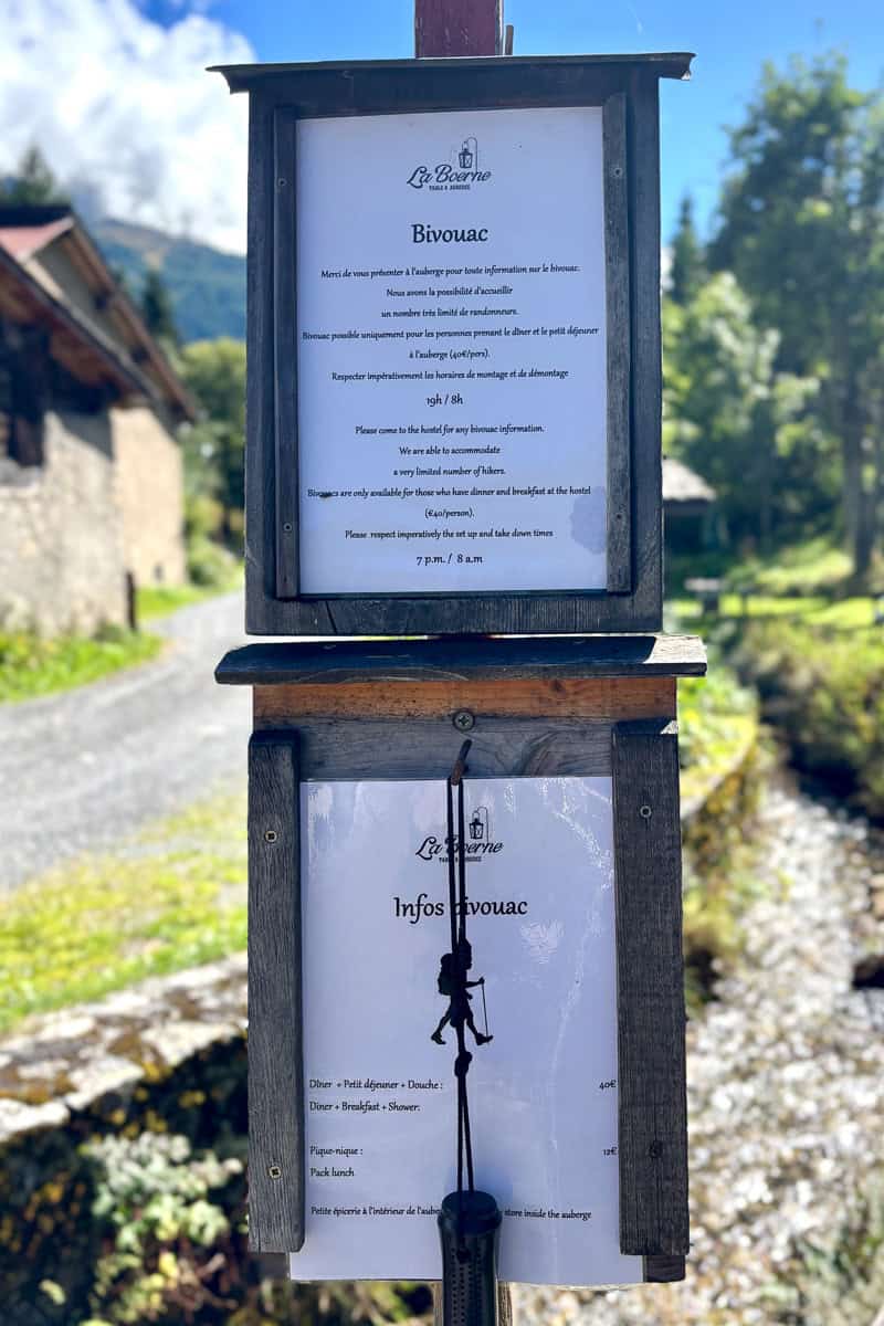 Informational sign with prices, check-in times and meal options for camping on the Tour de Mont Blanc at Auberge la Boerne.