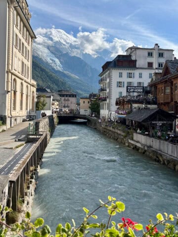 View of French Alps towering over French town with buildings on either side of canal.