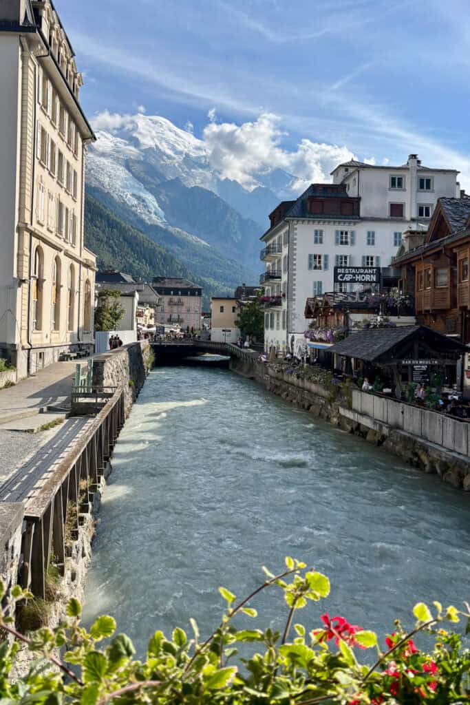 View of French Alps towering over French town with buildings on either side of canal.