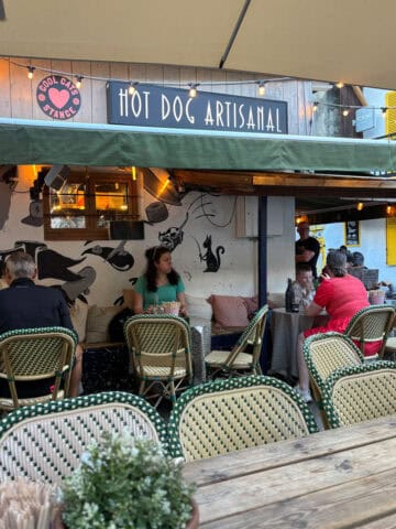 Tables and chairs under awning outside Cool Cats restaurant.