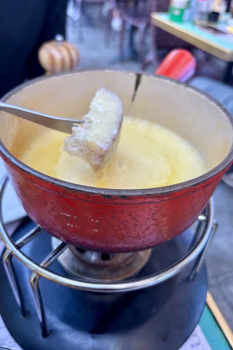 Fondue pot with piece of bread on fork.