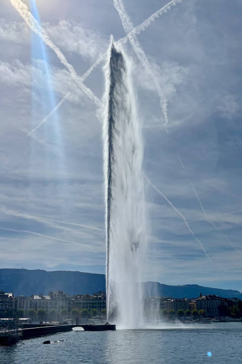 Jet d'Eau fountain as seen from boat tour with Geneva buildings in background.