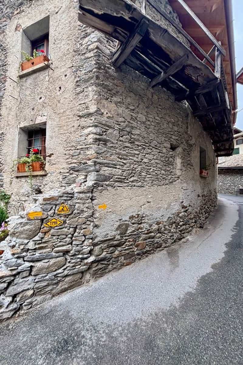 Stone building with attached trail markers for Tour du Mont Blanc.