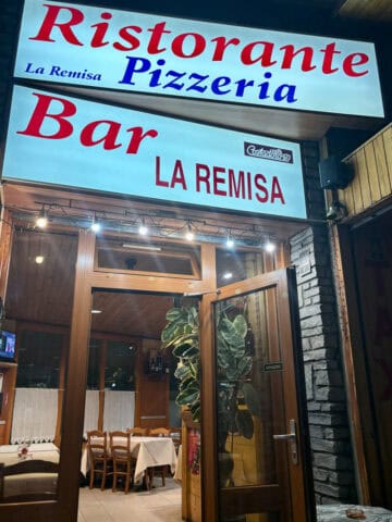 Lighted sign above doorway for Pizzeria La Remisa.