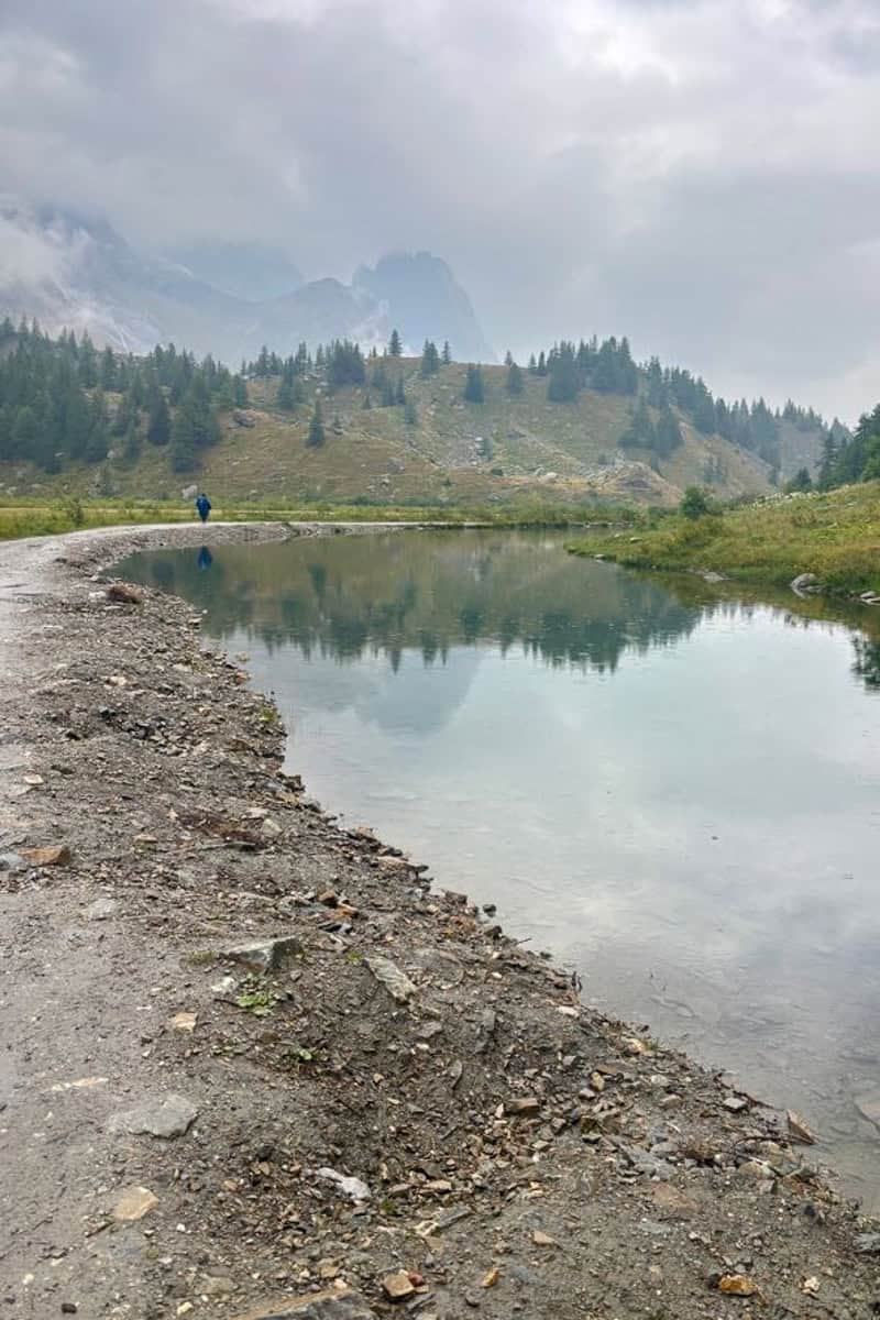 Pond seen alongside Tour du Mont Blanc trail with fog obscuring mountains in background.
