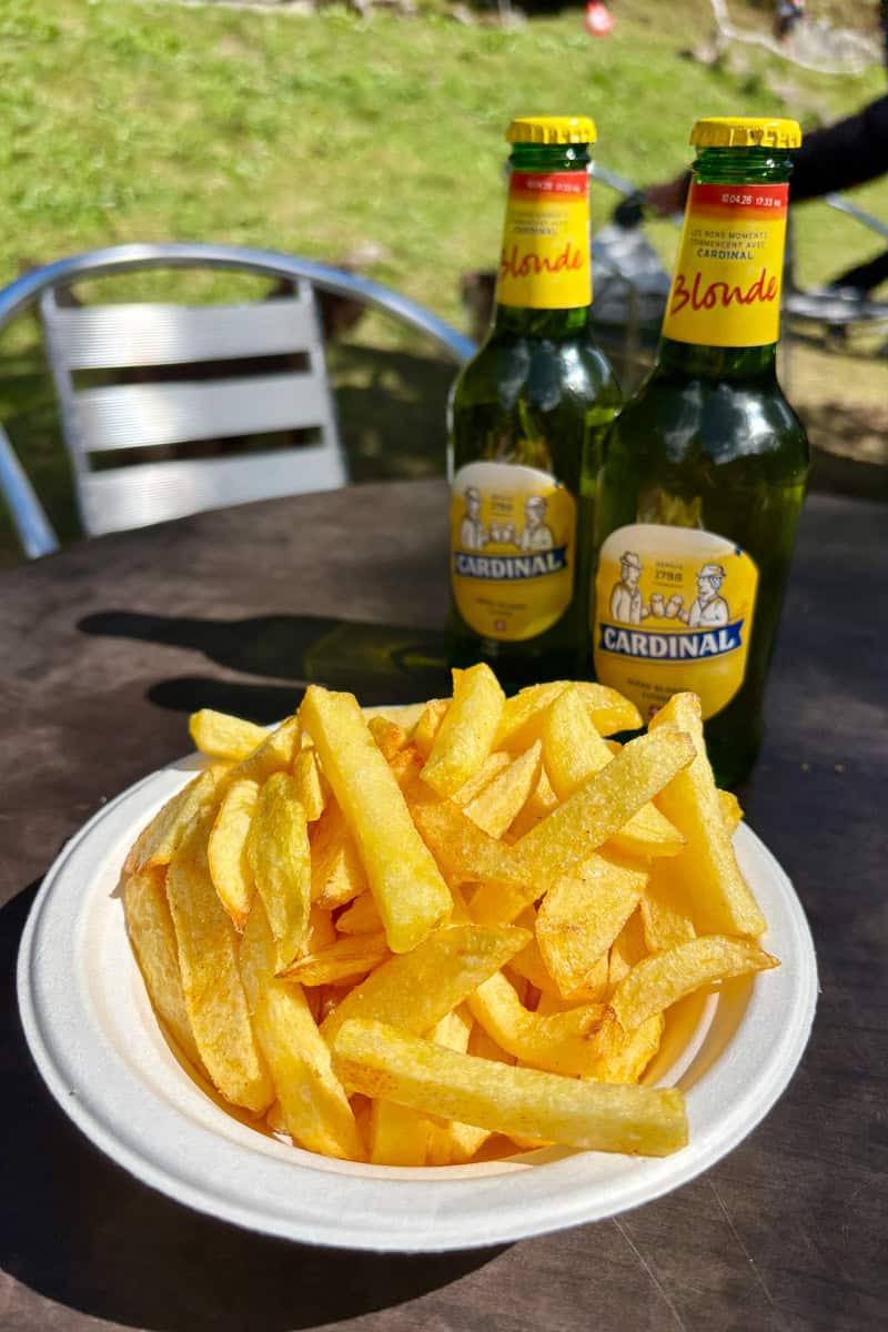 Two bottles of beer and bowl of fries.