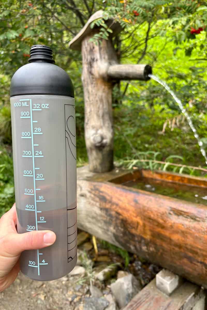 Thirty-two-ounce water bottle with water spigot in background, a key piece of backpacking gear for the Tour du Mont Blanc.
