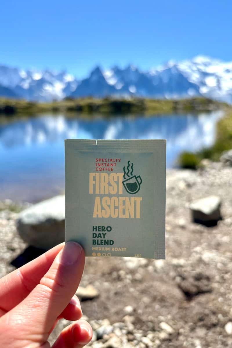 instant coffee packet in foreground of an alpine lake.