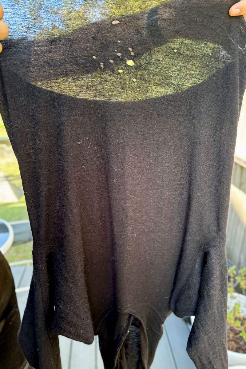 Wool hoodie held up to display holes from wear and tear on the Tour du Mont Blanc.
