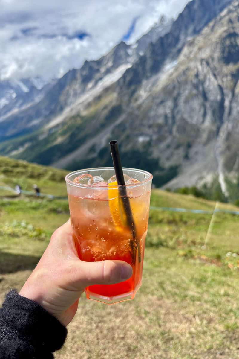 Cocktail in glass with Alpine slope in background.