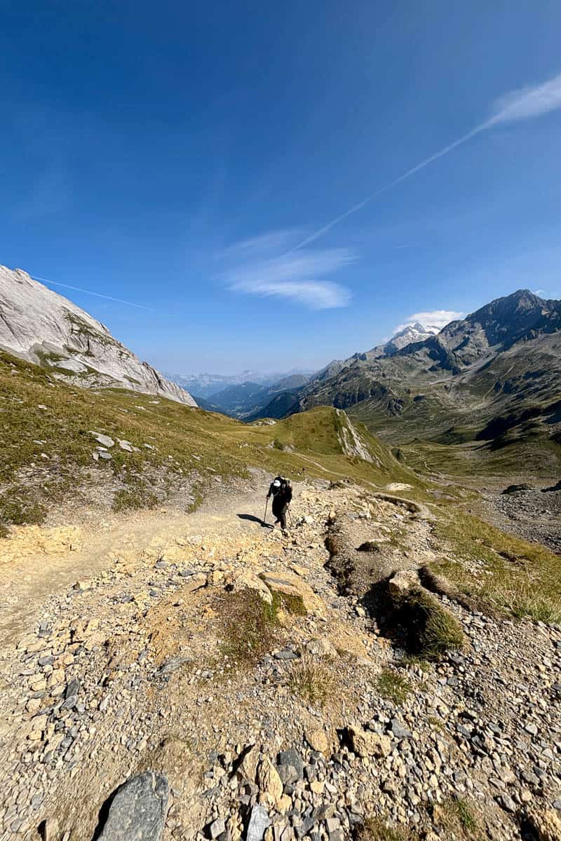 Hiker ascending slope of loose rocks on the Tour du Mont Blanc.