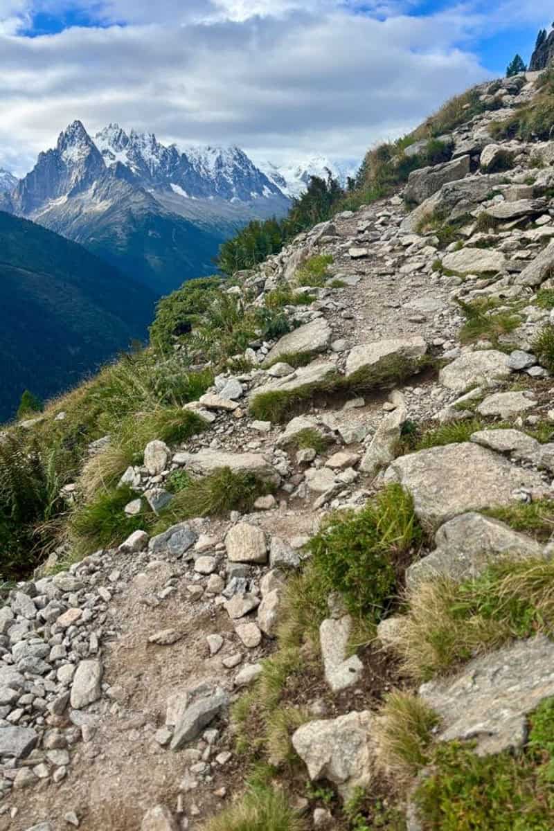 Steep rocky trail with view of snow-covered peaks in the distance on Stage 10 of the Tour du Mont Blanc.