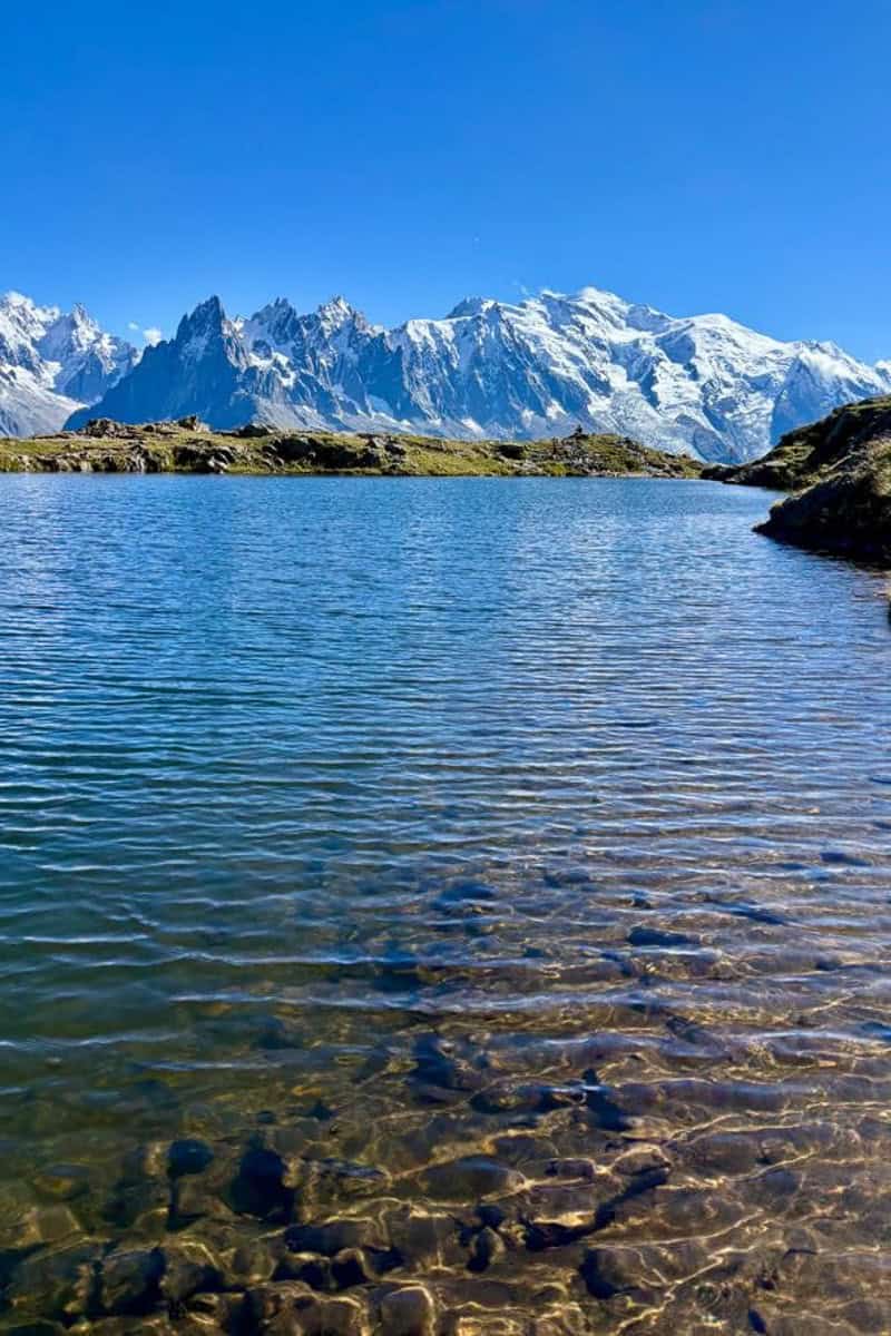 View across lake of snowy mountain range on Tour du Mont Blanc stage 10.