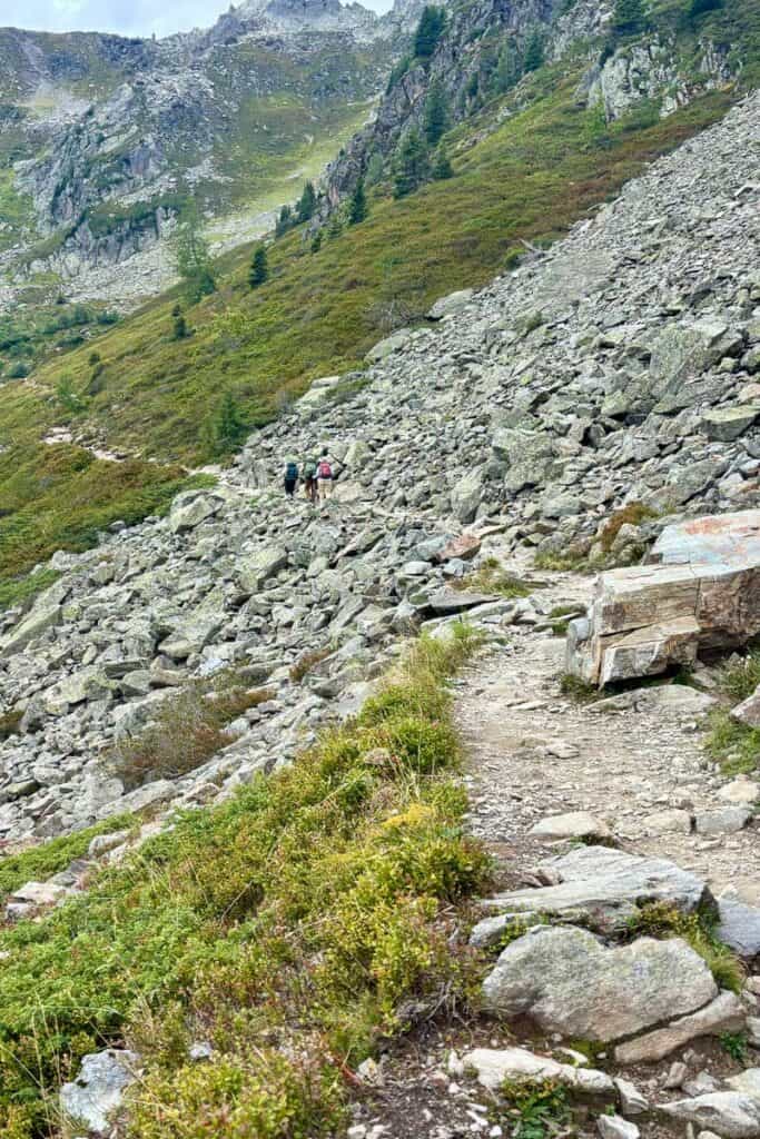 Hikers on trail through rock avalanche field on Stages 10 and 11 of the Tour du Mont Blanc.