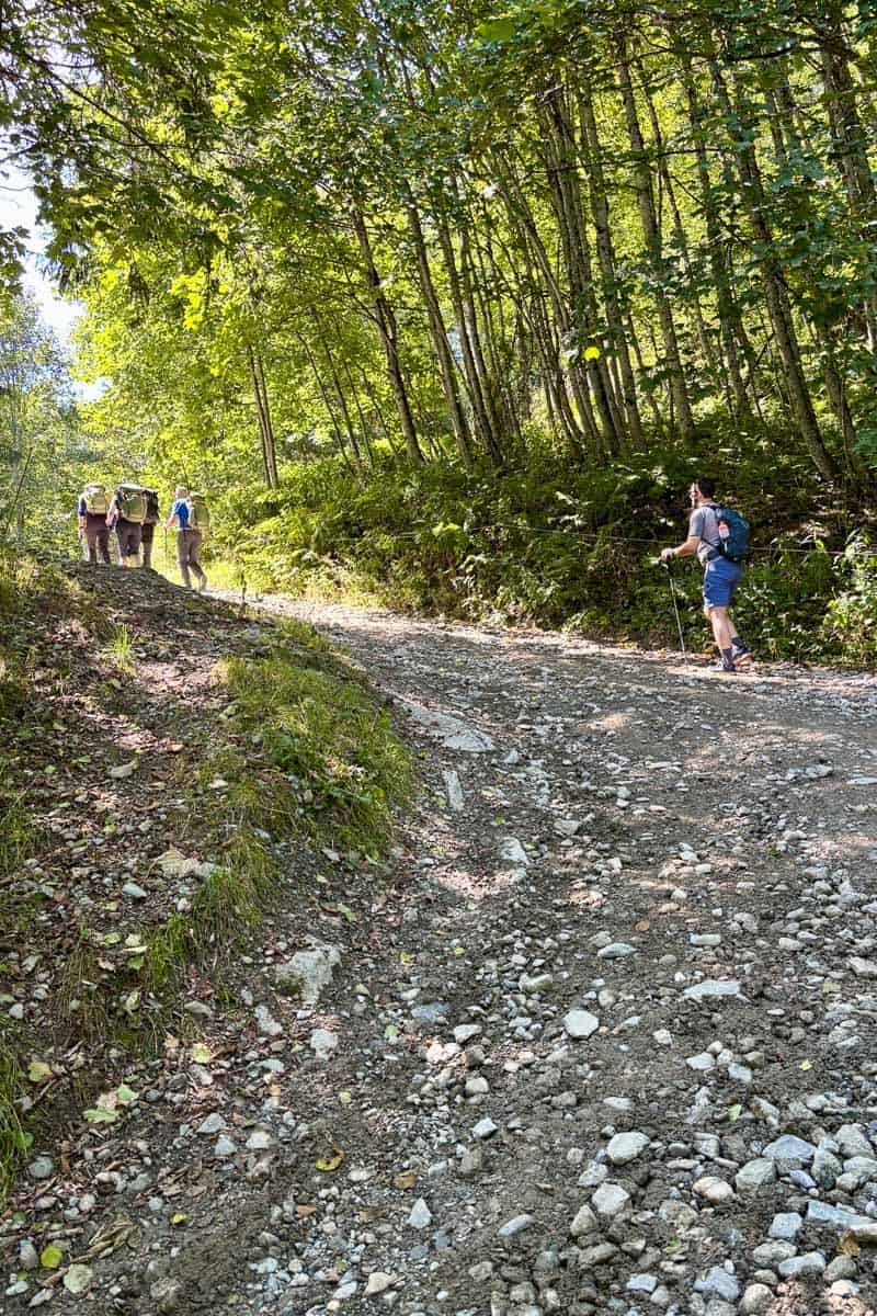 Backpackers going uphill on loose gravel road.