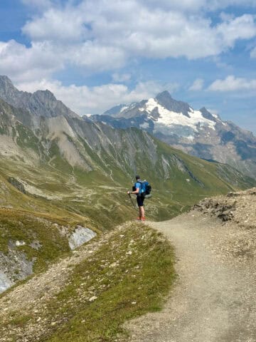 Backpacker standing above Alpine valley viewing mountain peaks.
