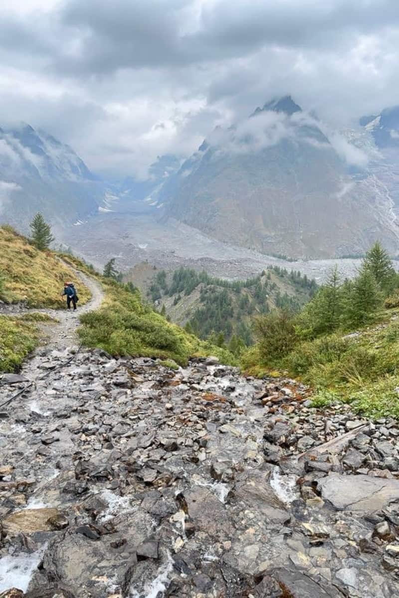 Rocky trail with view of cloud-covered mountains.