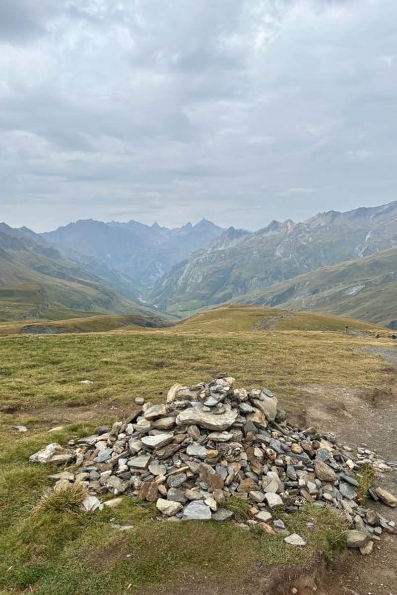 Trail marker made up of numerous rocks, with mountain views.