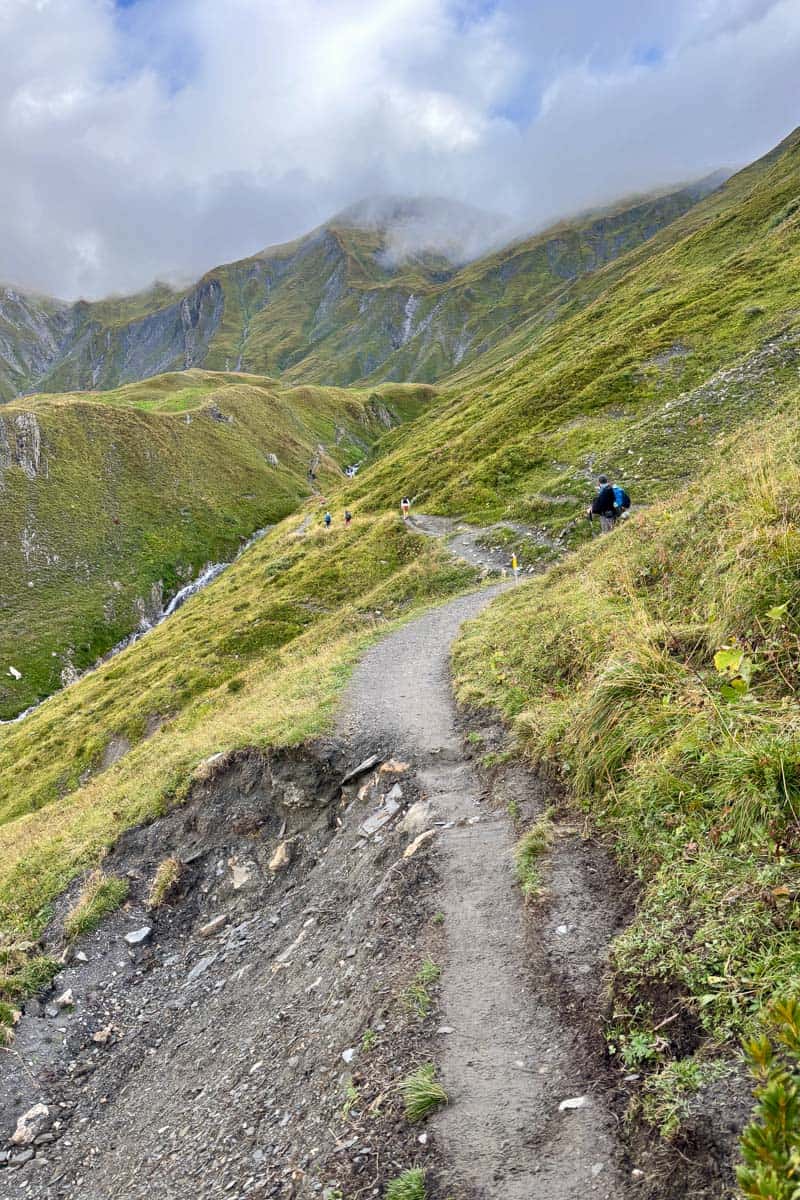 Trail along steep mountainside overshadowed by clouds on Stage 6 of the Tour du Mont Blanc.