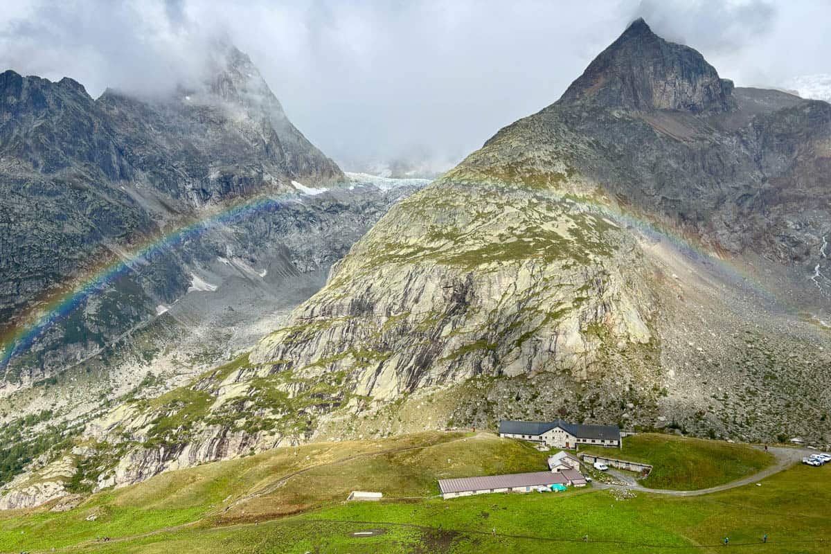 Faint rainbow stretching across alpine valley.