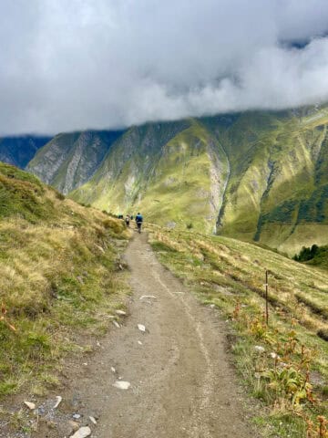 Dirt trail on Stage 6 of the Tour du Mont Blanc with view of steep mountainside covered by thick cloud.