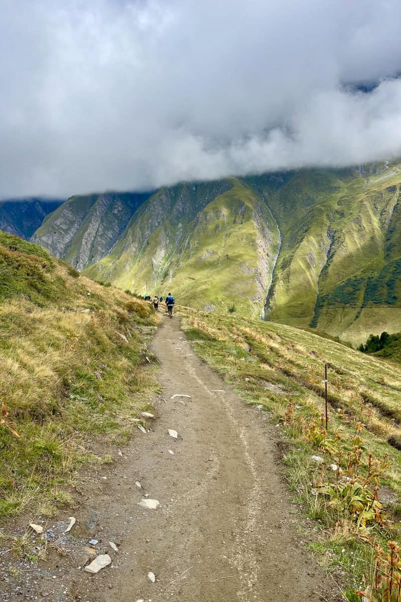 Dirt trail on Stage 6 of the Tour du Mont Blanc with view of steep mountainside covered by thick cloud.