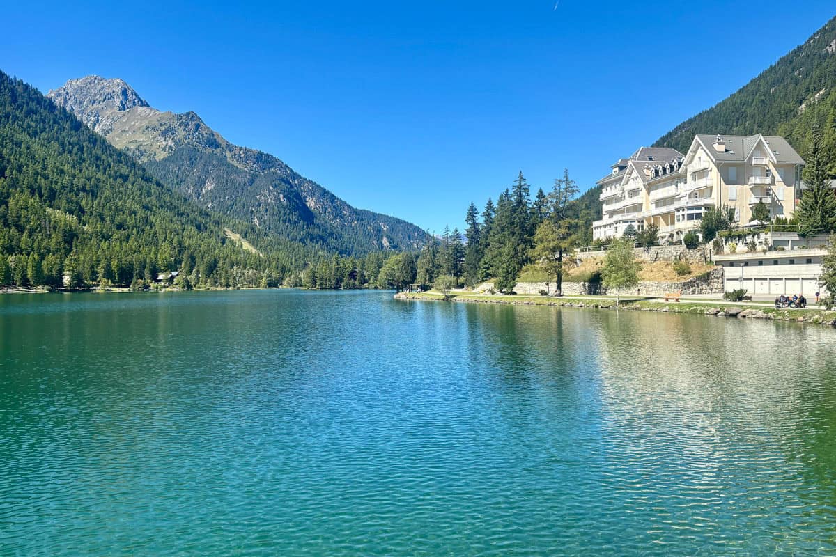 Lake at Champex Lac, with forested mountainsides and large villa on the shore.