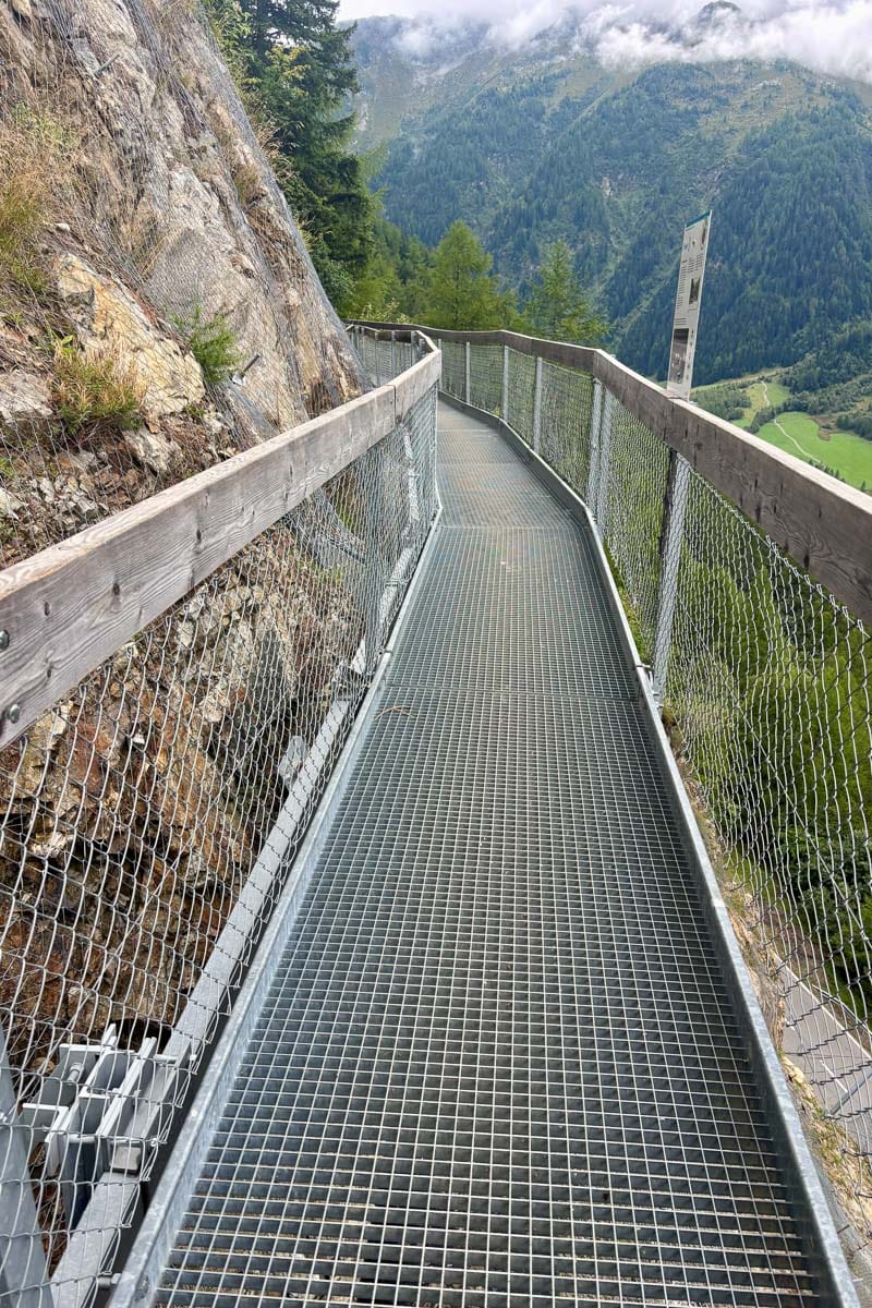 Metal walkway overhanging alpine valley.