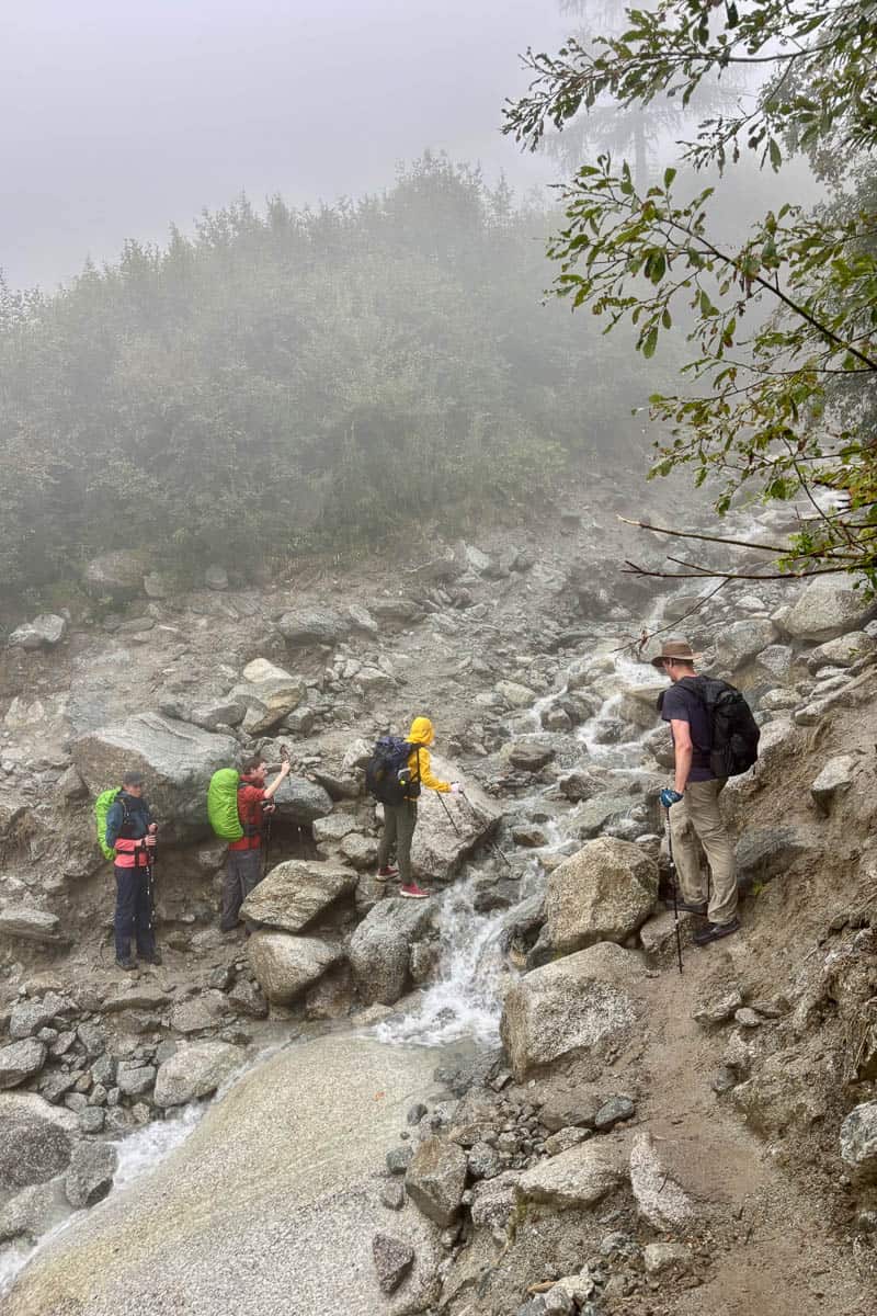 Backpackers crossing small waterfall on Stage 8 of the Tour du Mont Blanc.