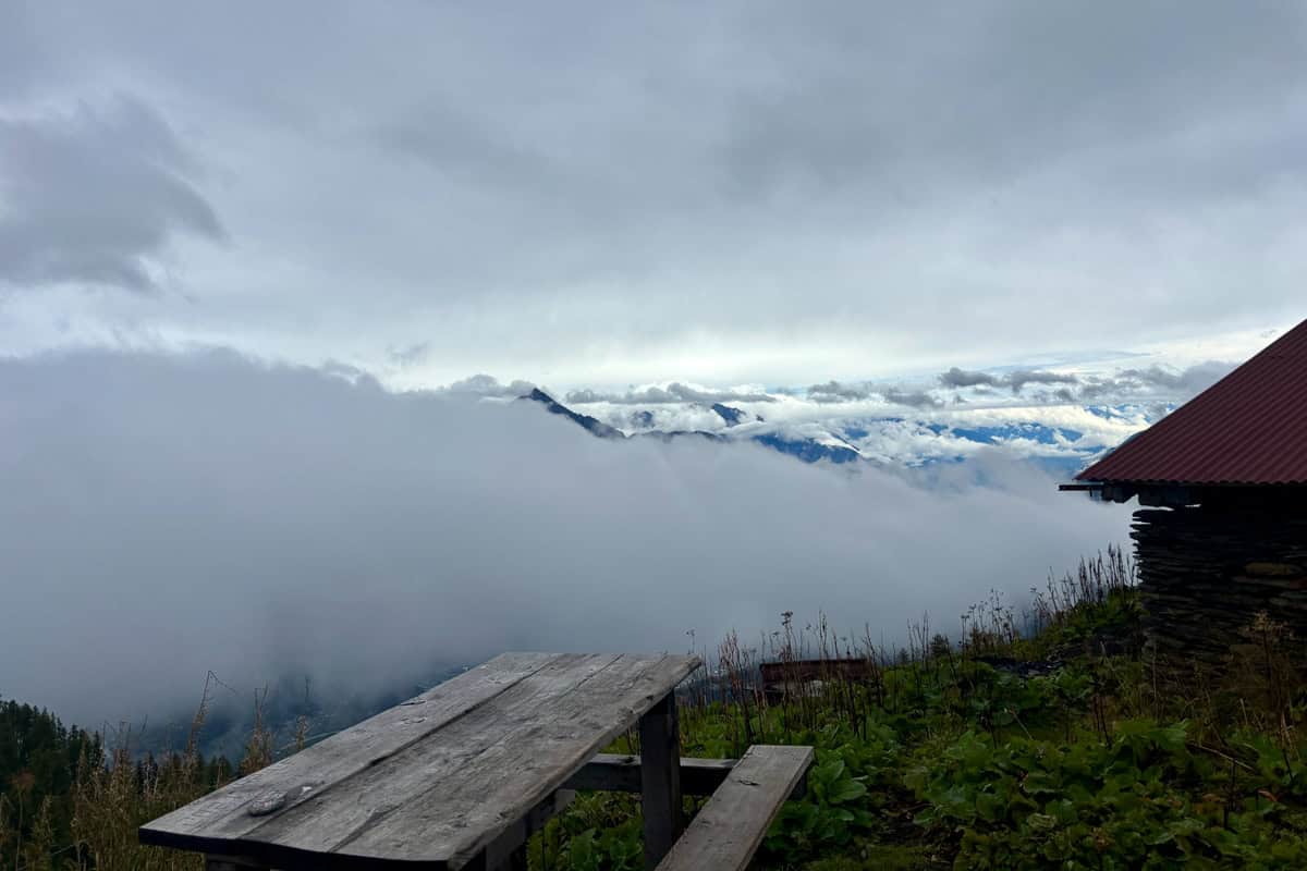 Wooden picnic table overlooking foggy valley.