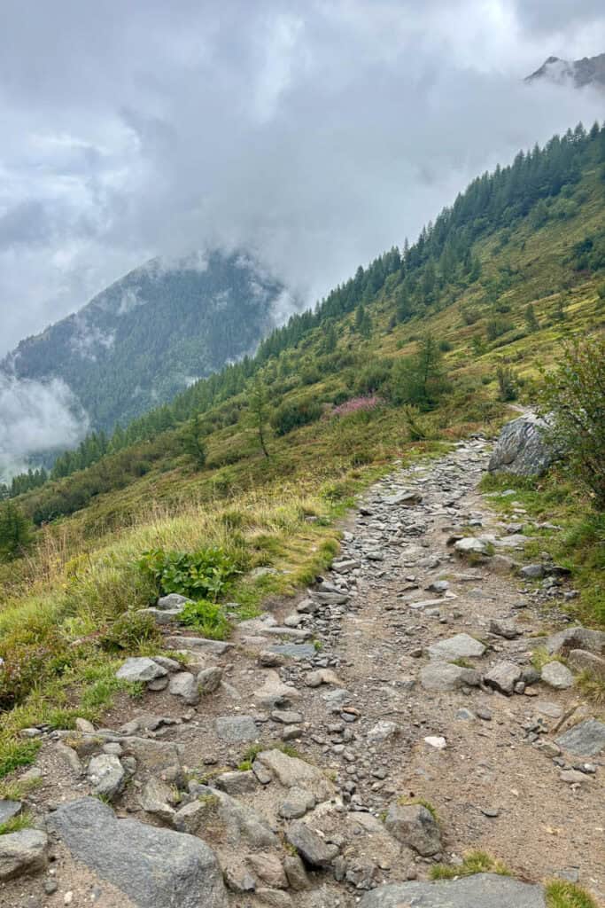 Green mountainside with distant peak obscured by cloud.