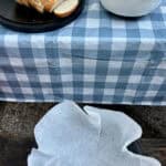 Sliced bread loaf next to bowl of pumpkin custard mixture and Dutch oven lined with parchment paper.