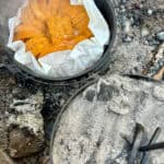 Lid lifted away from dutch oven to reveal campfire baked French toast.