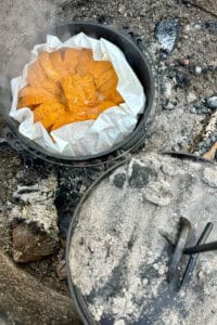 Lid lifted away from dutch oven to reveal campfire baked French toast.