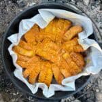 Dutch oven lined with parchment paper and filled with campfire baked French toast.
