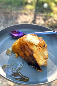 Plate of campfire baked French toast topped with butter and syrup.