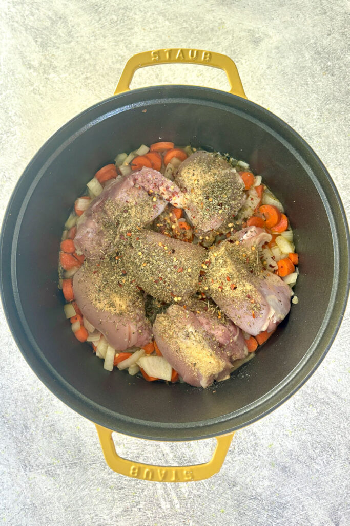 Dutch oven with onions, carrots, chicken, water and seasonings.