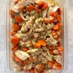 Cooked chicken, carrots, and onions in storage container.