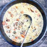 Cast-iron dutch oven filled with campfire creamy chicken soup.