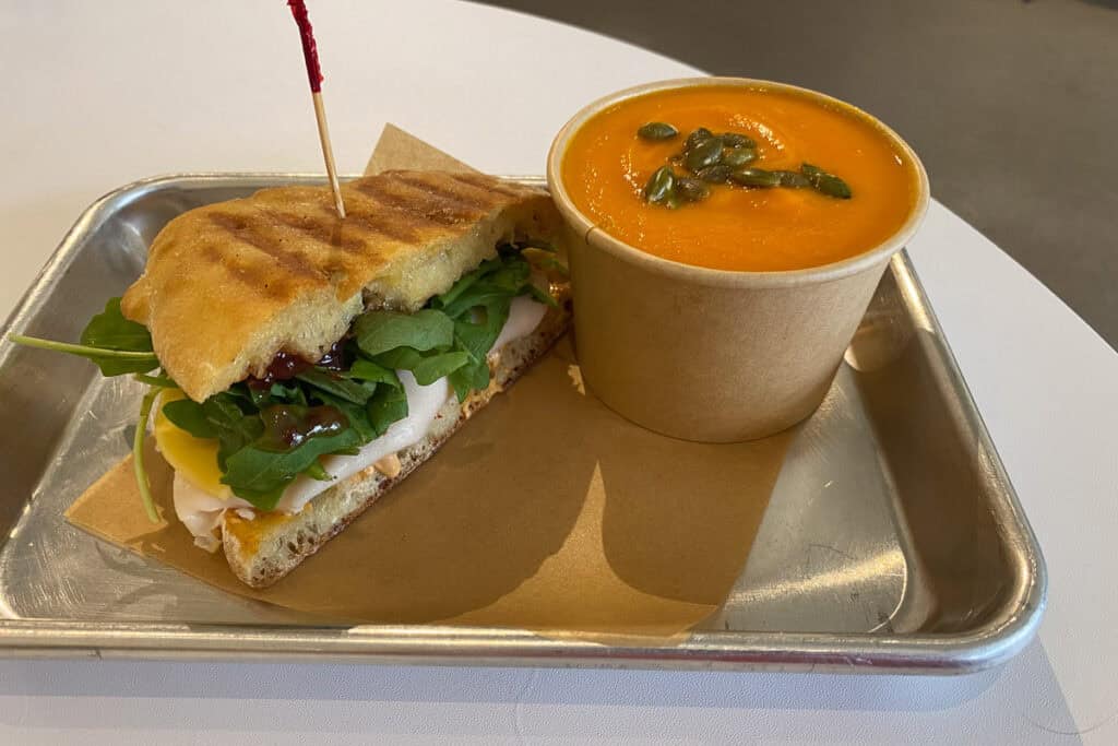 Turkey gouda and jam sandwich with cup of coconut carrot soup.