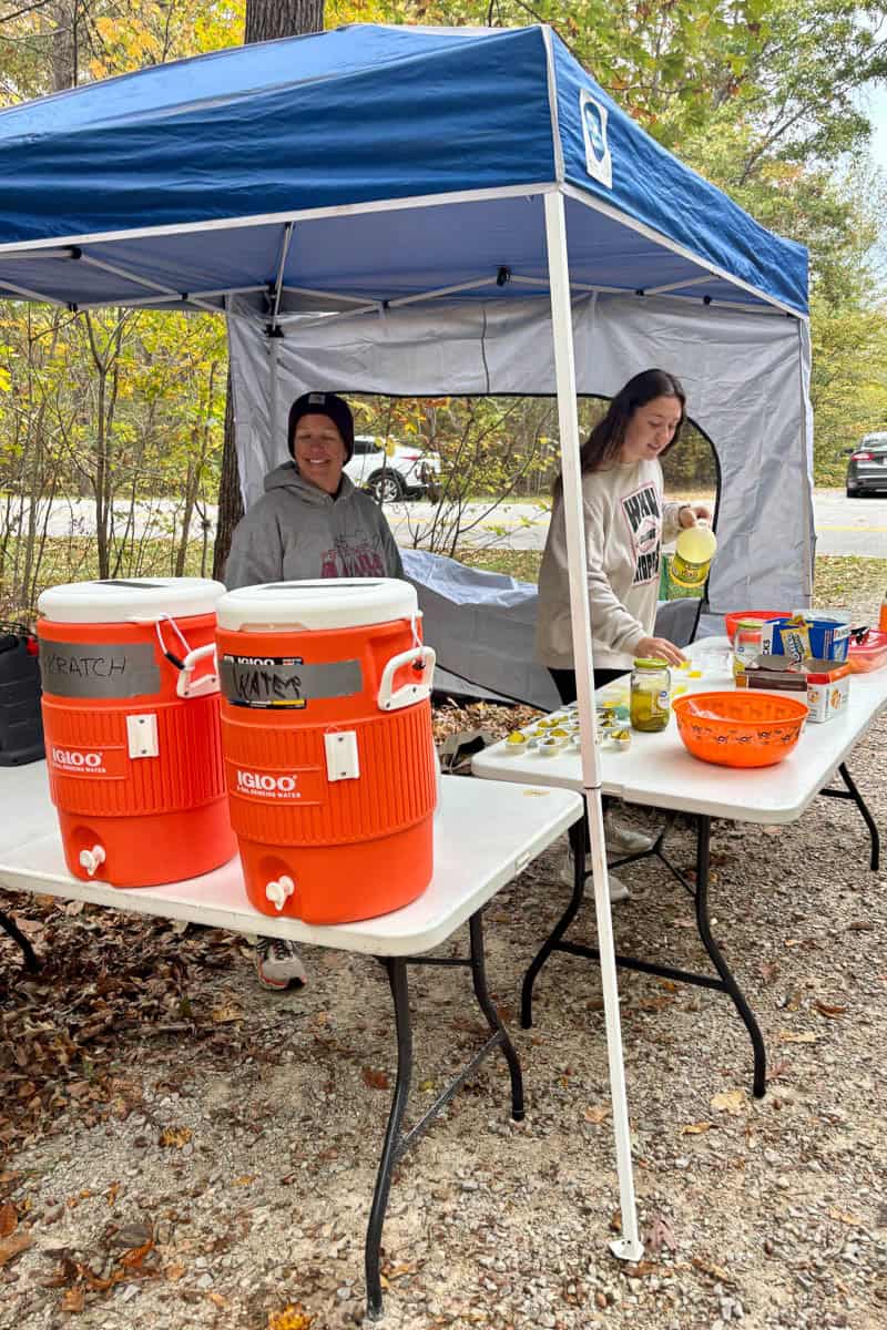 Volunteers at Mammoth Cave race aid station with coolers of water and bowls of snacks.